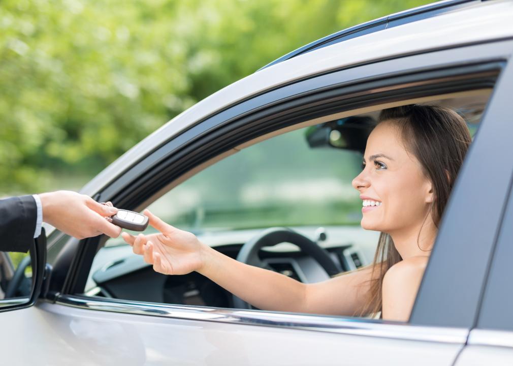 A young woman receives keys to a new car