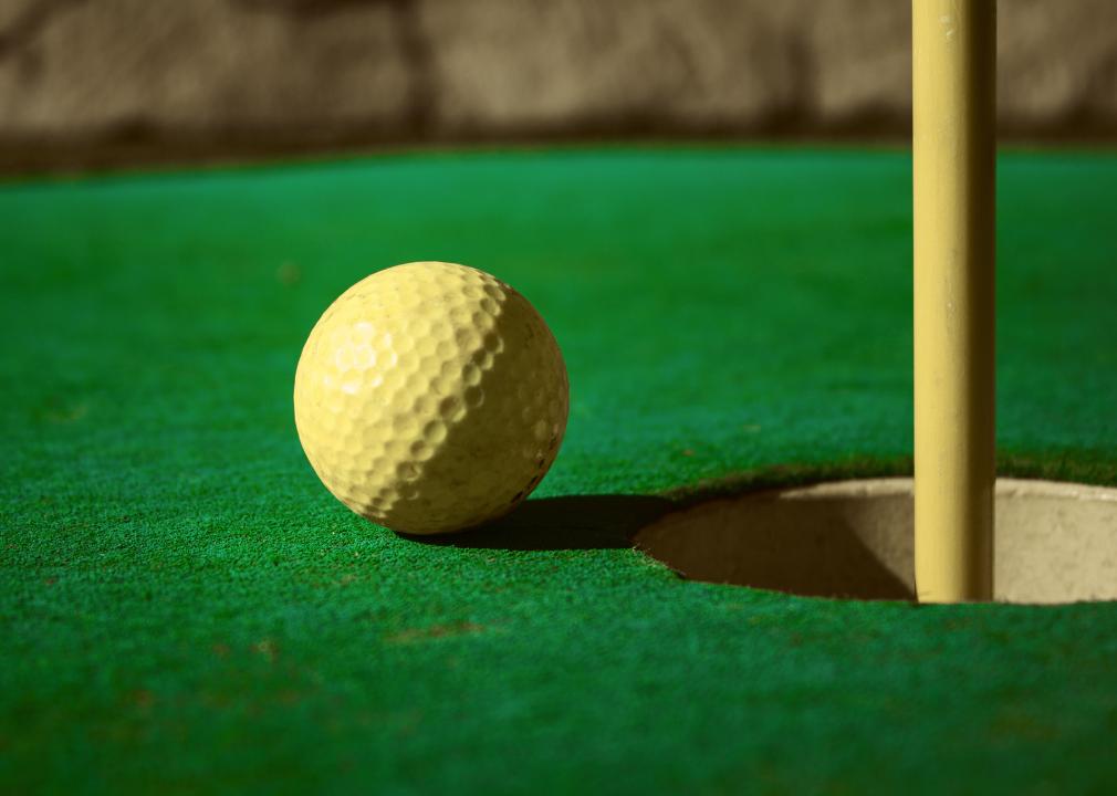 Mini golf ball on green headed towards hole