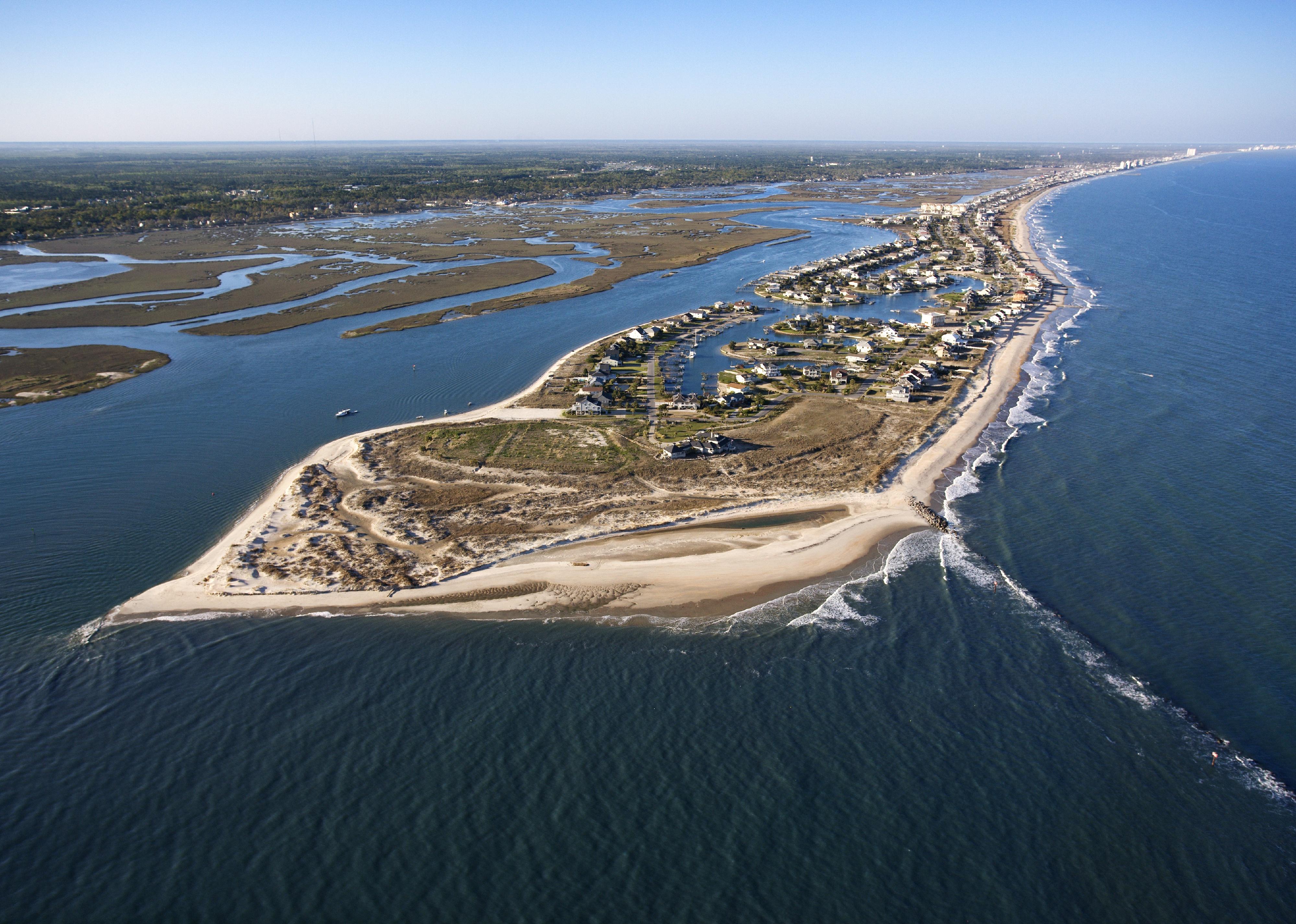 Aerial view of peninsula with beach and buildings in Murrells Inlet.