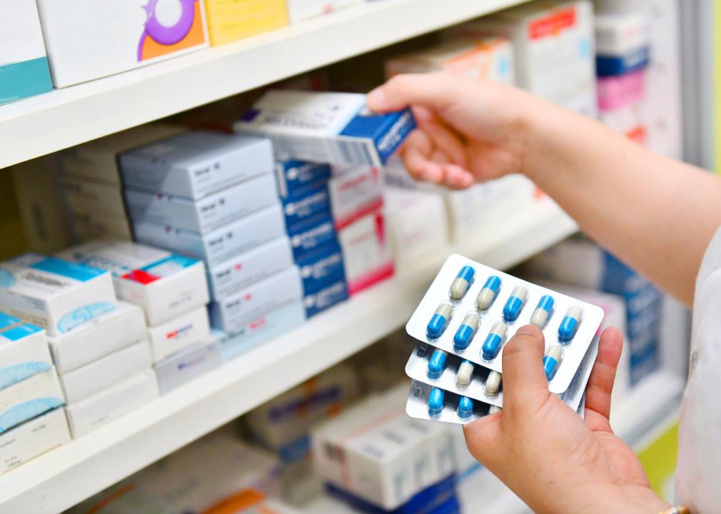 Pharmacist holding medicine box and capsule pack.