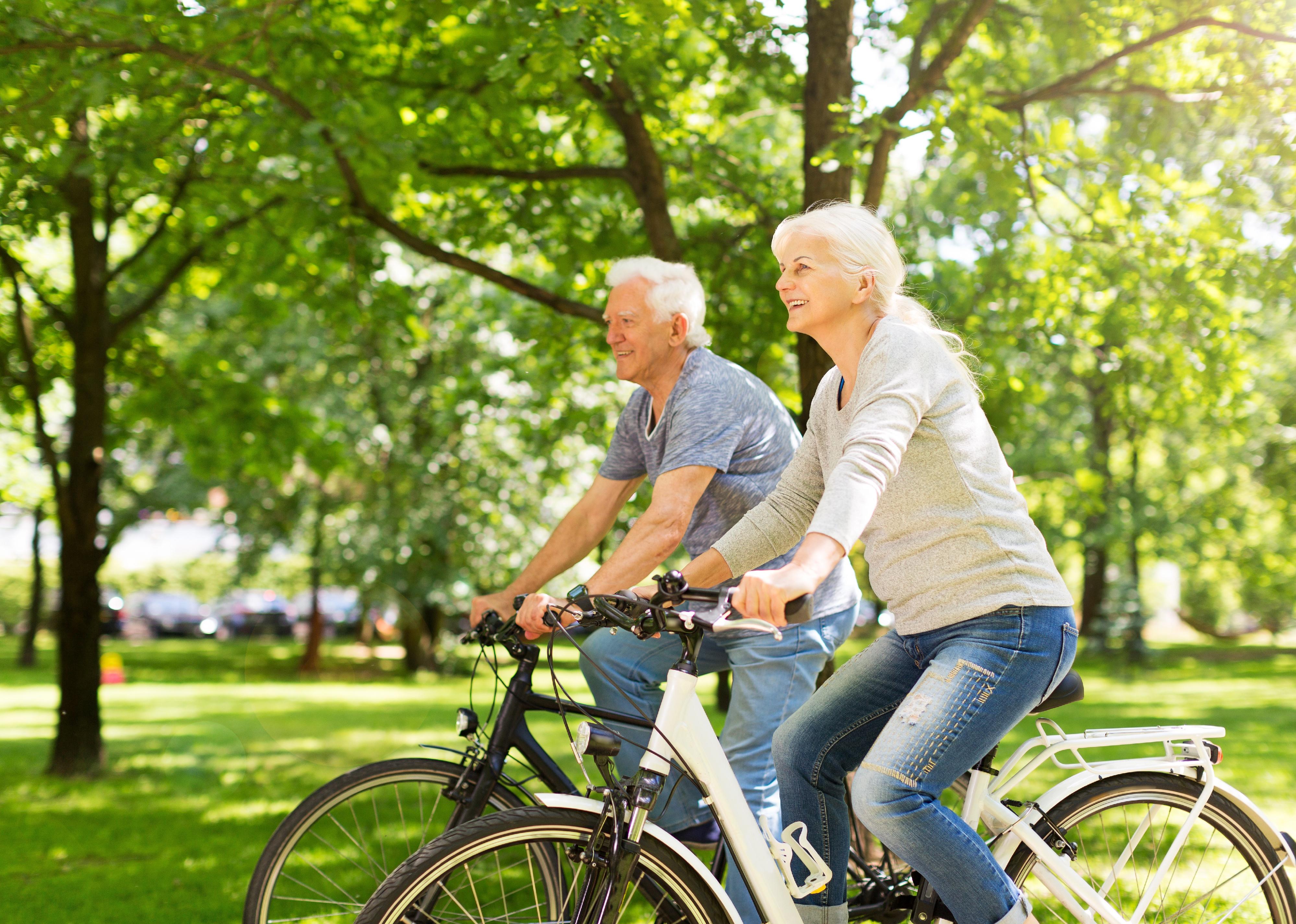 Senior couple riding bikes in a park.