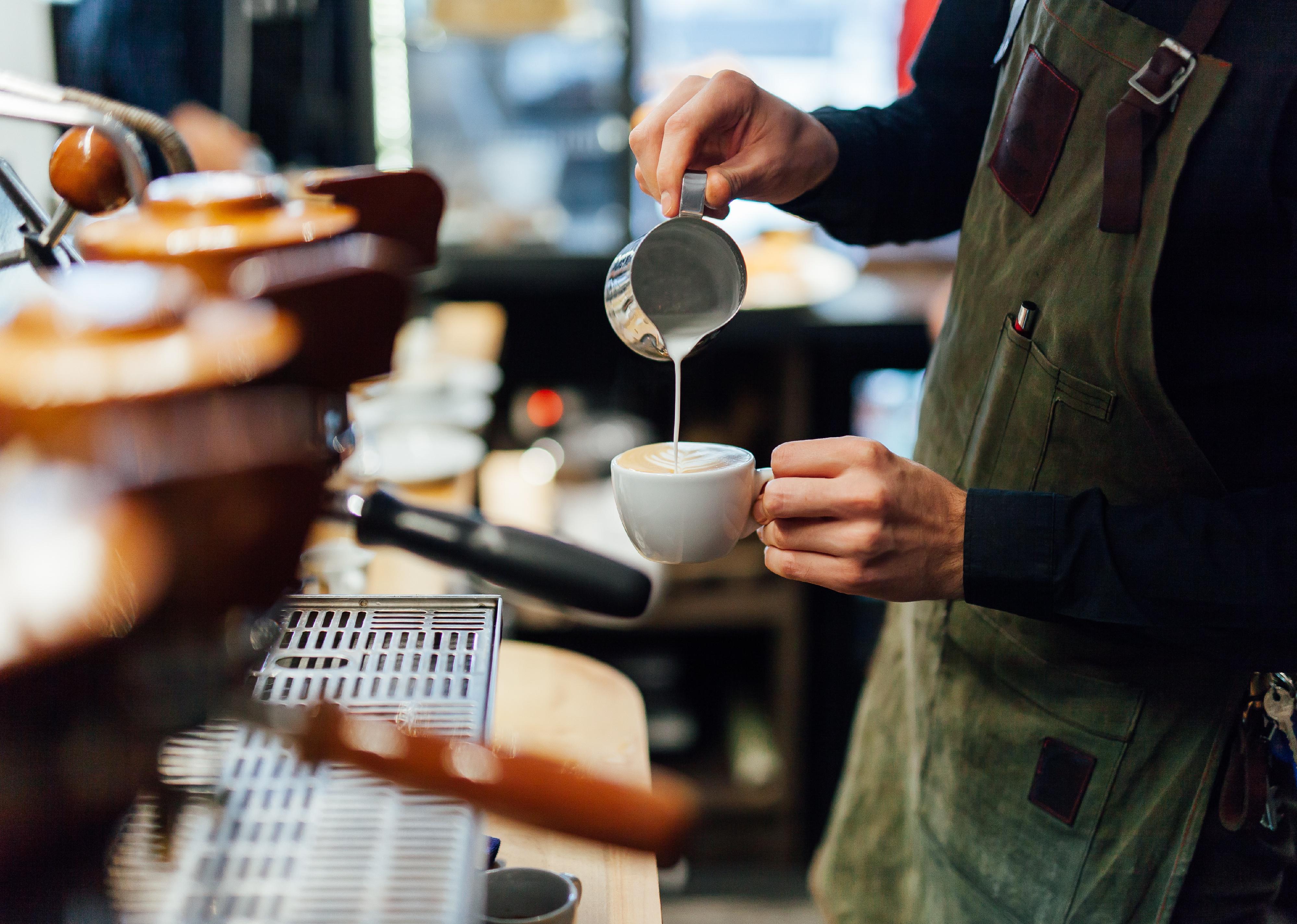 Side view of a barista making cappuccino.