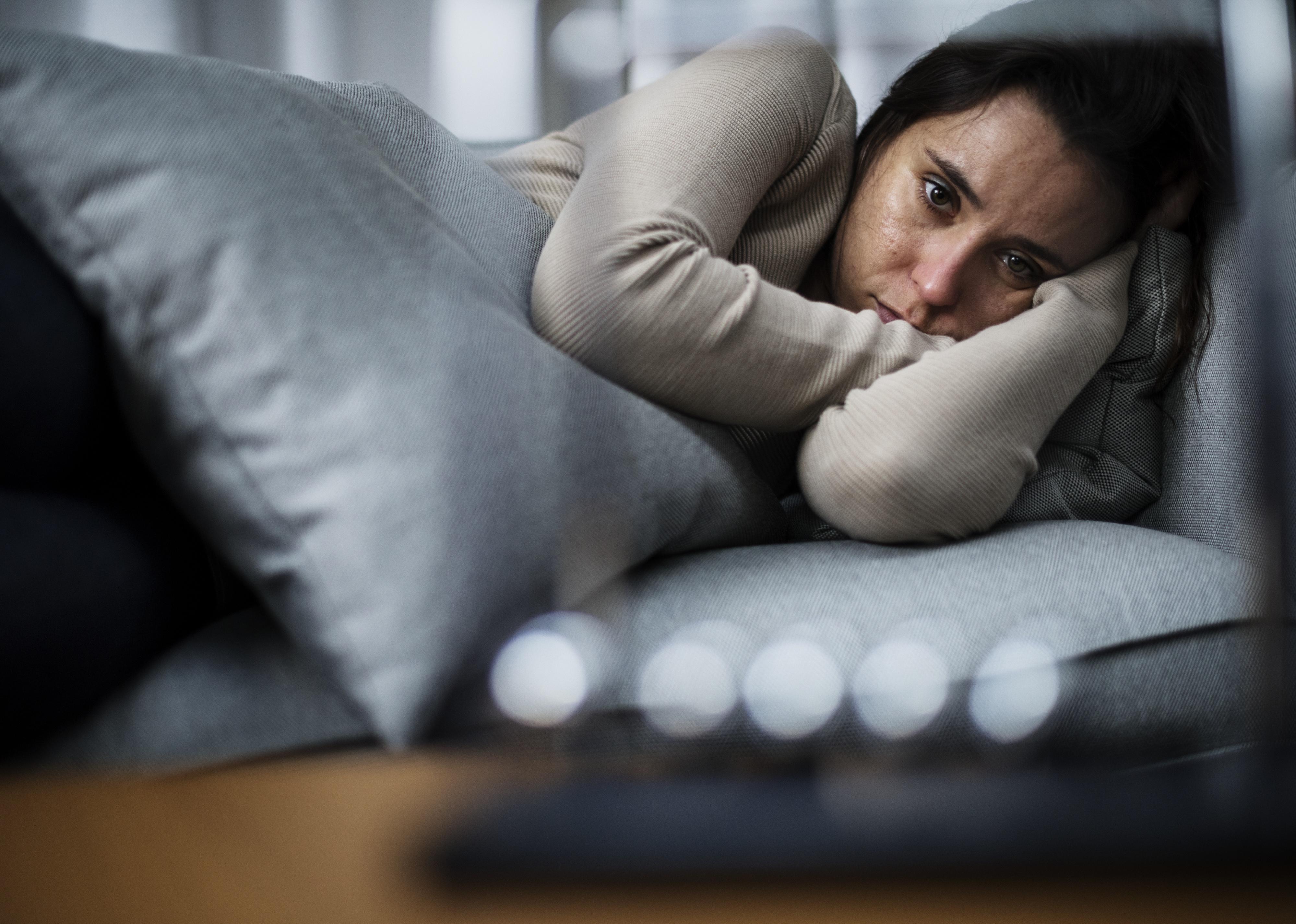 Depressed woman laying in bed.