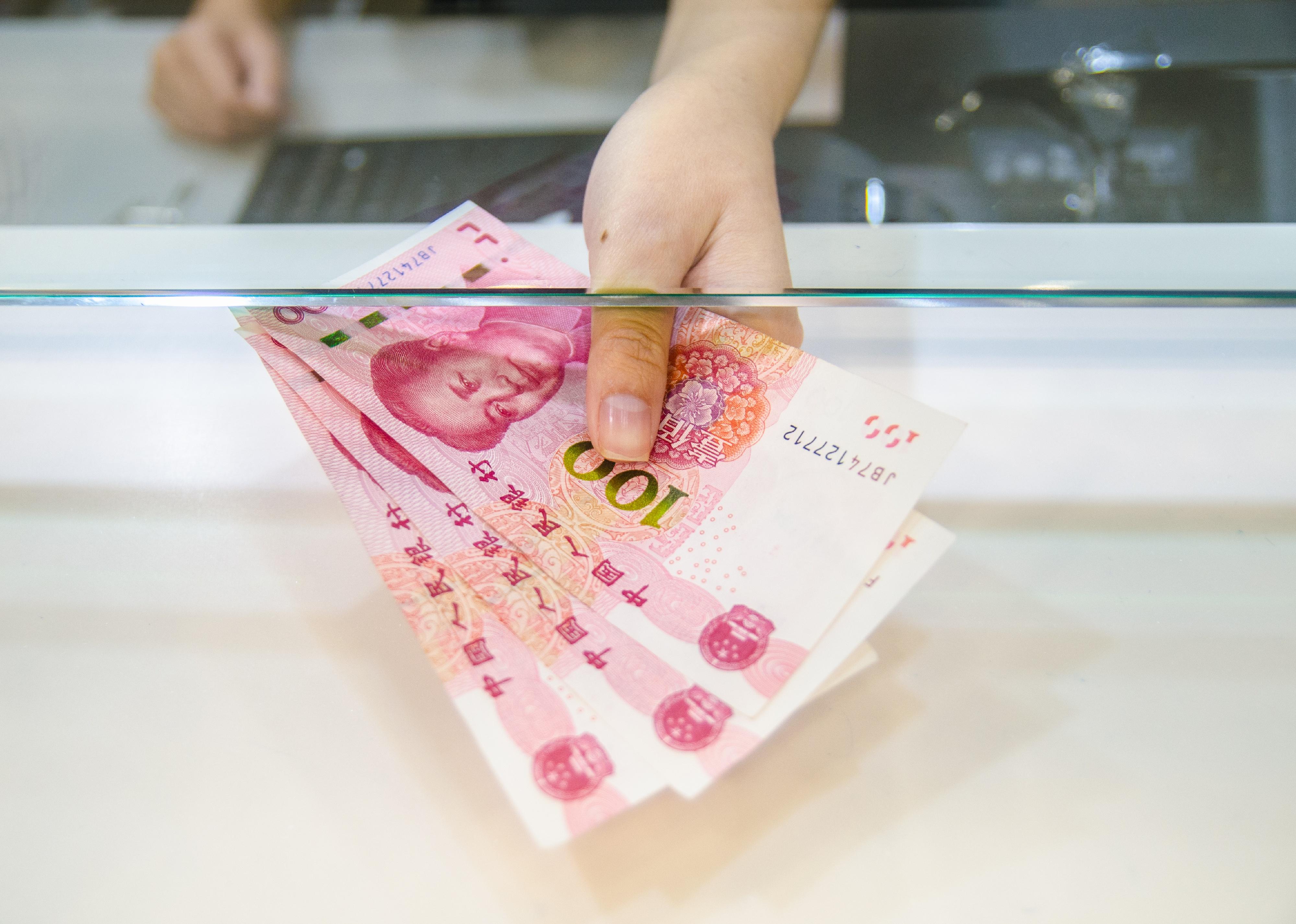Person handing Chinese yuan across a counter. 
