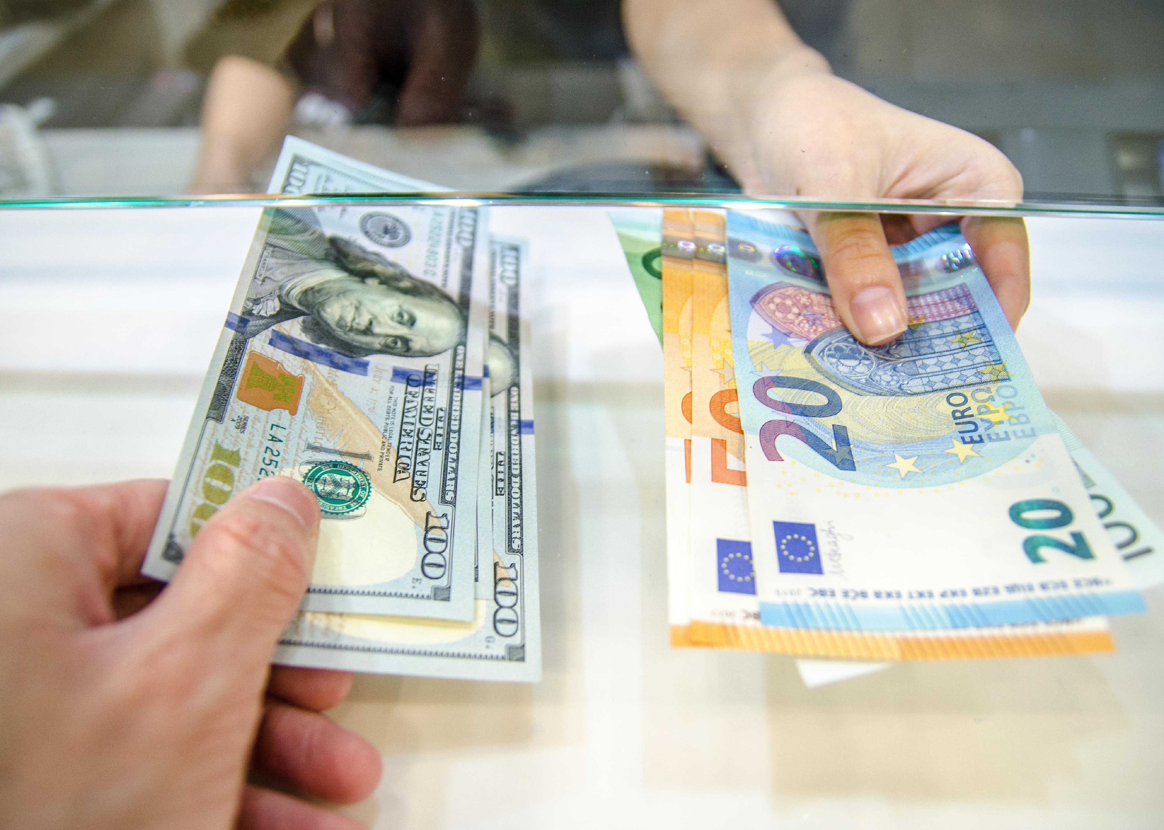 Two people exchanging dollars for euros.