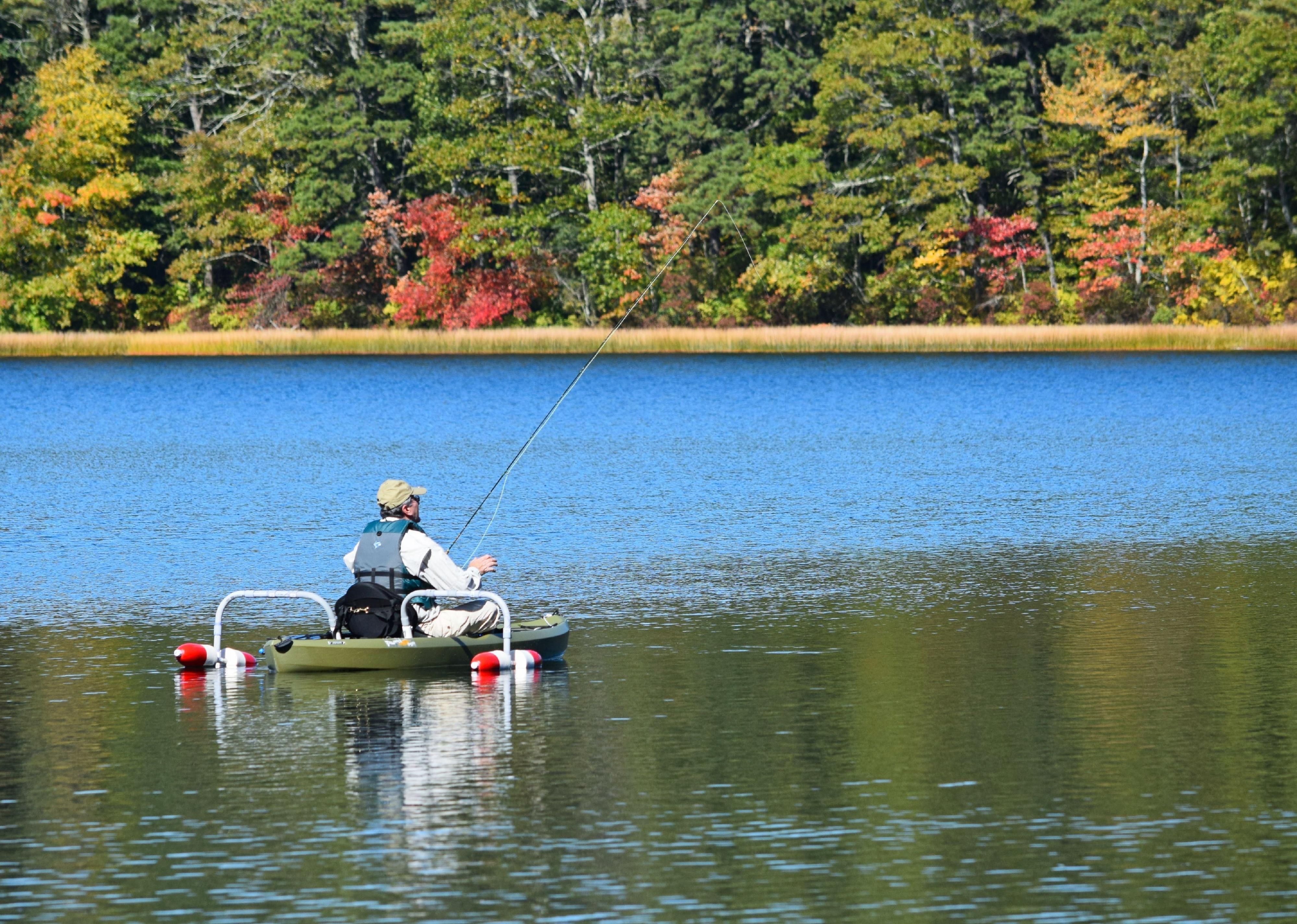 Person fishing on small boat on lake.