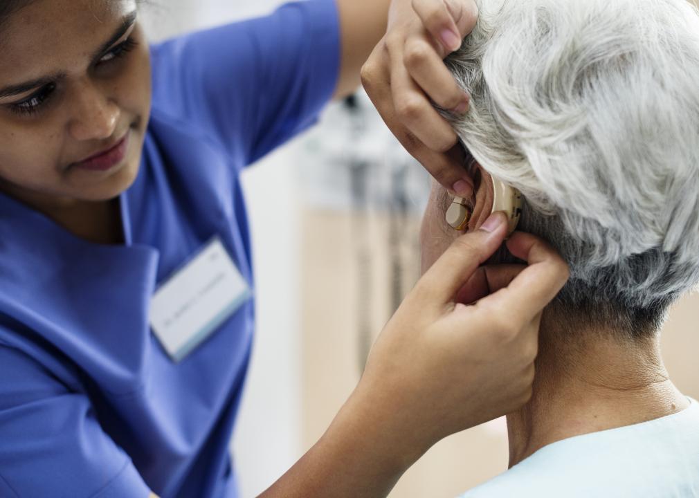 An elderly woman getting a hearing aid.