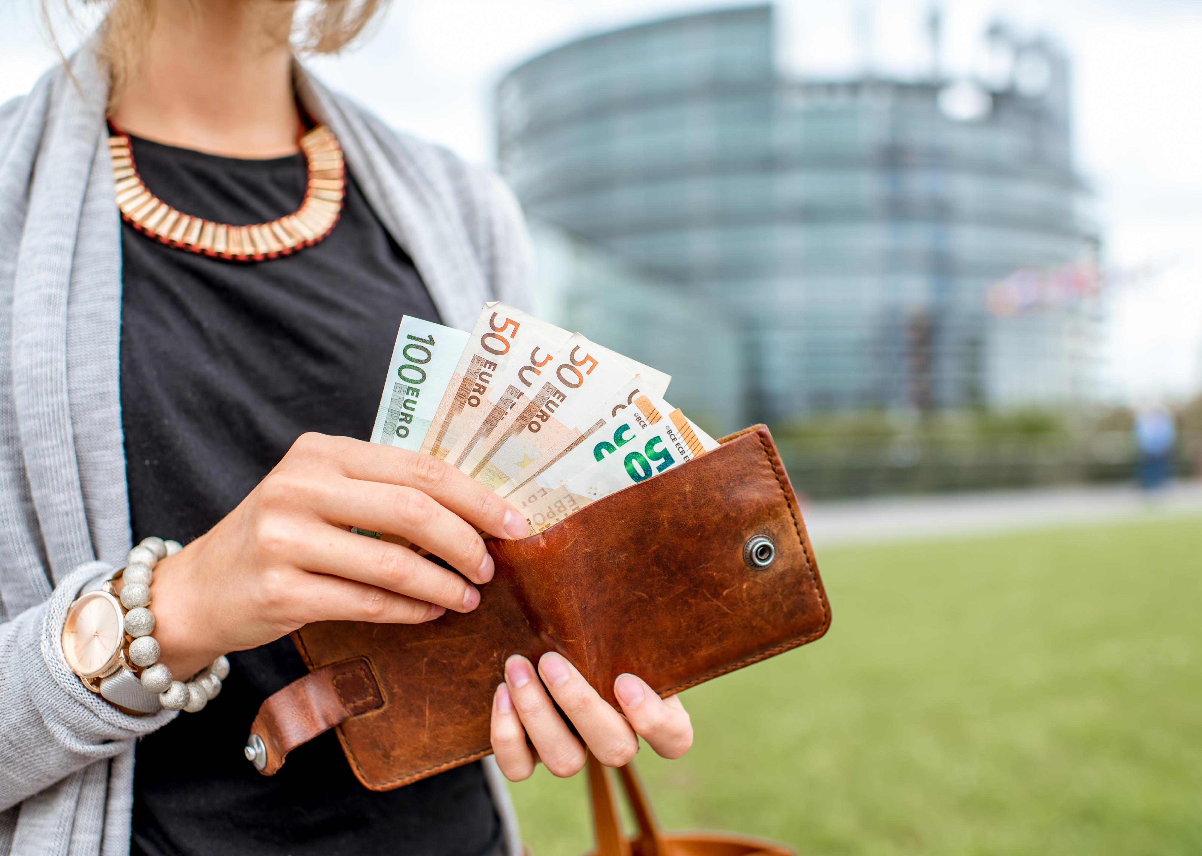 Close-up view of two hands holding open wallet with Euros