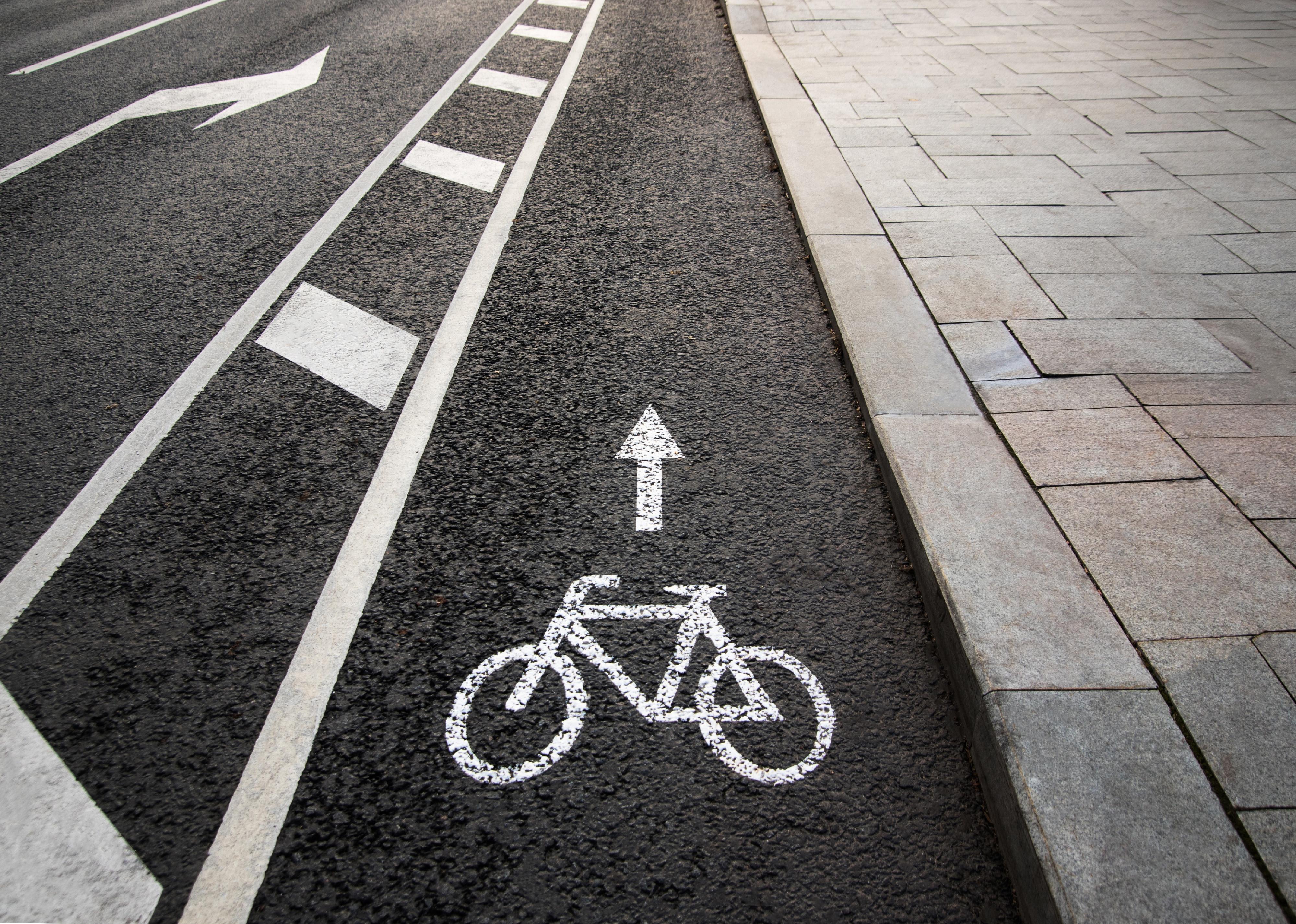 A white bike painted on asphalt next to a painted buffer line.