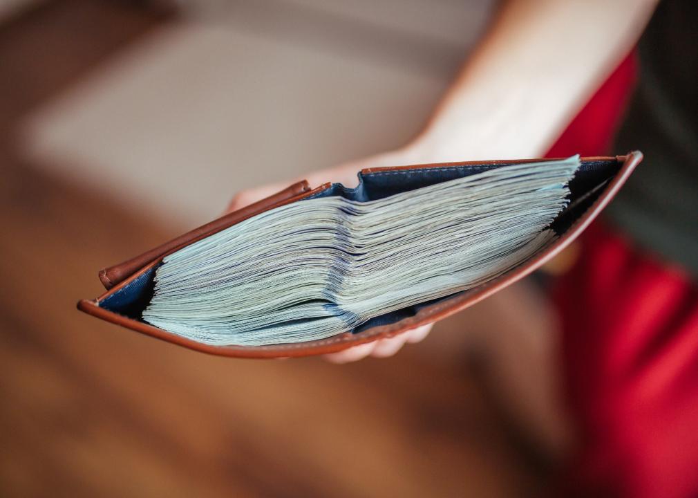 Wallet in hand with a large stack of money