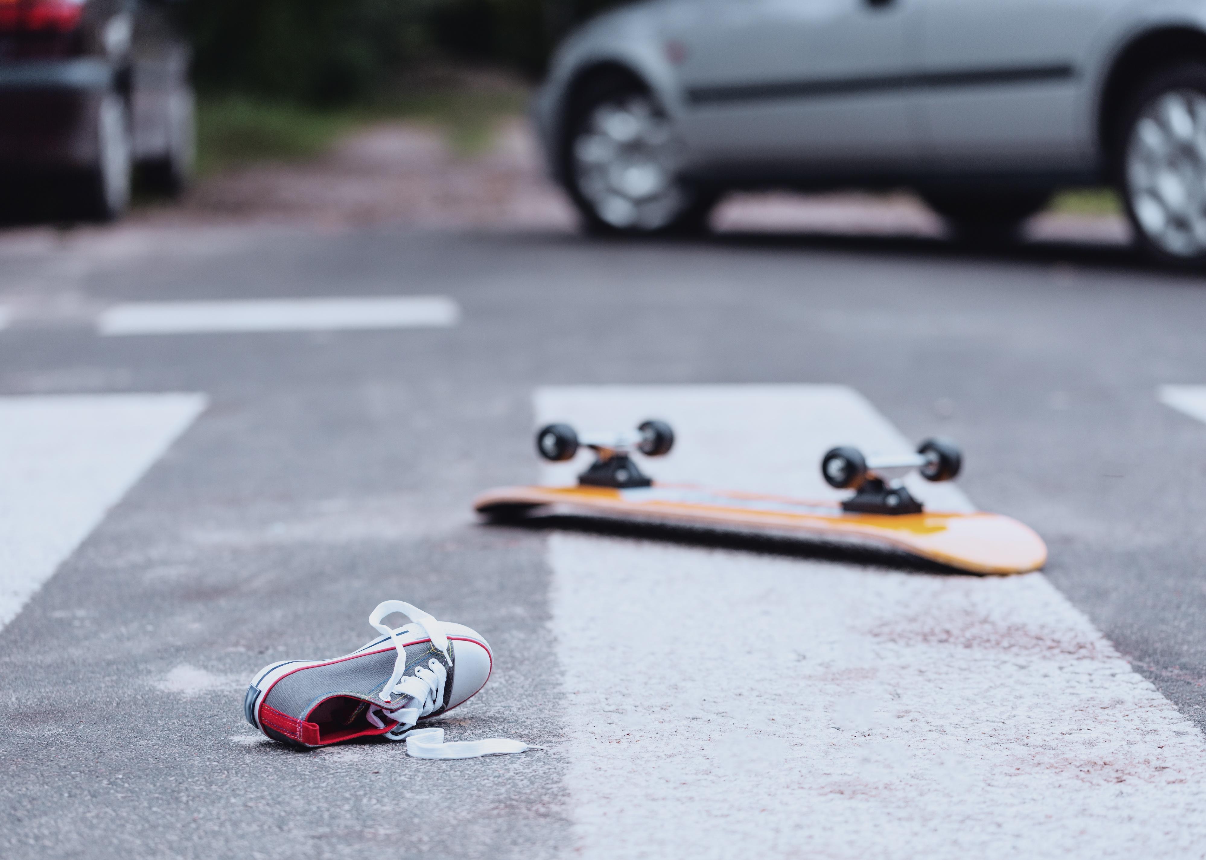 Teenager's shoe and skateboard lying on a pedestrian crossing