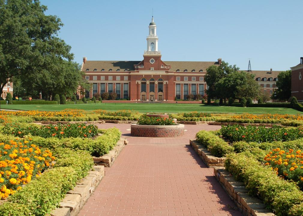 An orange flower garden in front of a red brick university building.