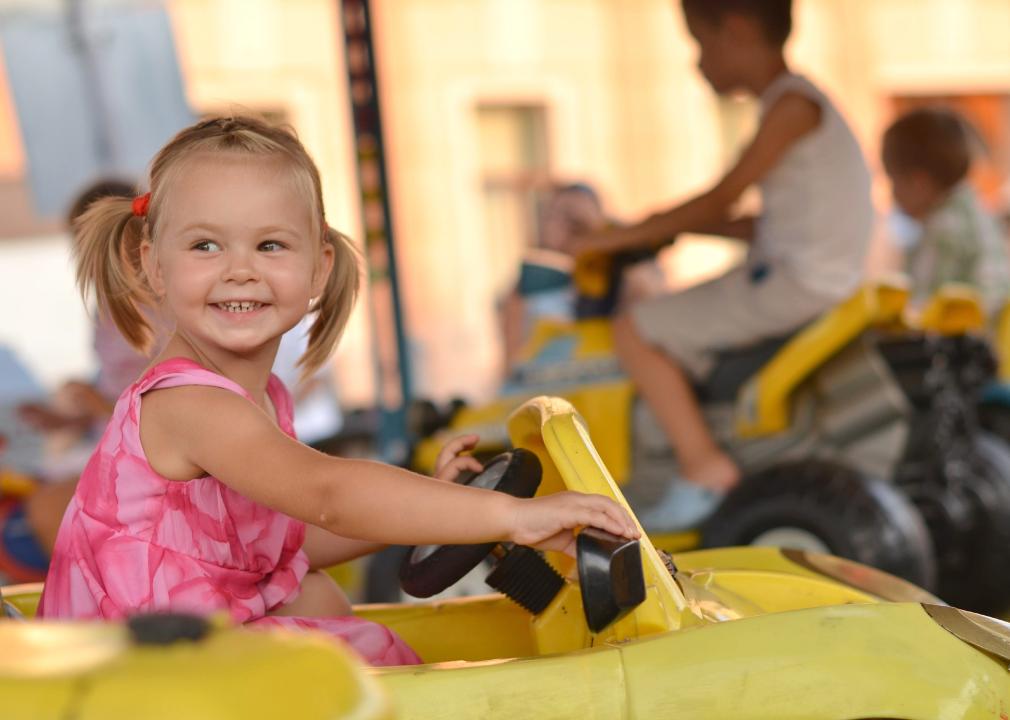 Young girl on a theme park ride smiling. 