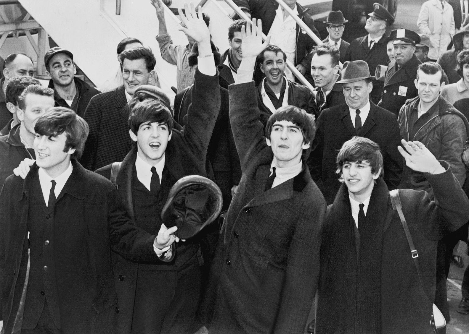 The Beatles waving in a crowd.