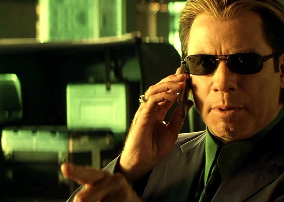 John Travolta in a suit wearing dark glasses.