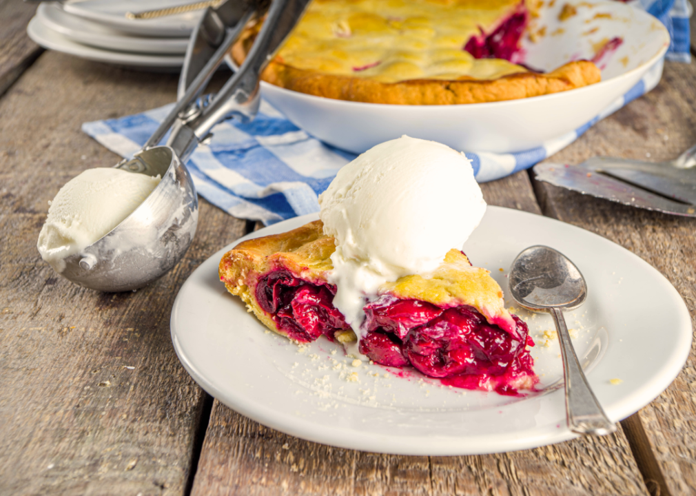 A piece of tart cherry pie with ice cream.