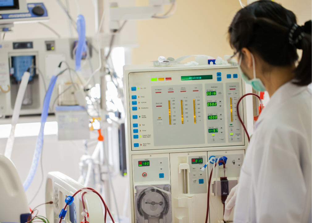 A medical professional presses buttons on a dialysis machine.