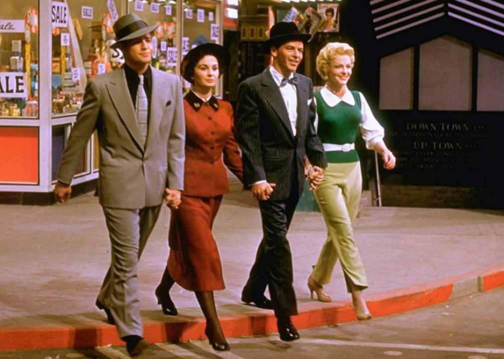 Marlon Brando, Frank Sinatra, Jean Simmons, and Vivian Blaine walking hand in hand on the set.