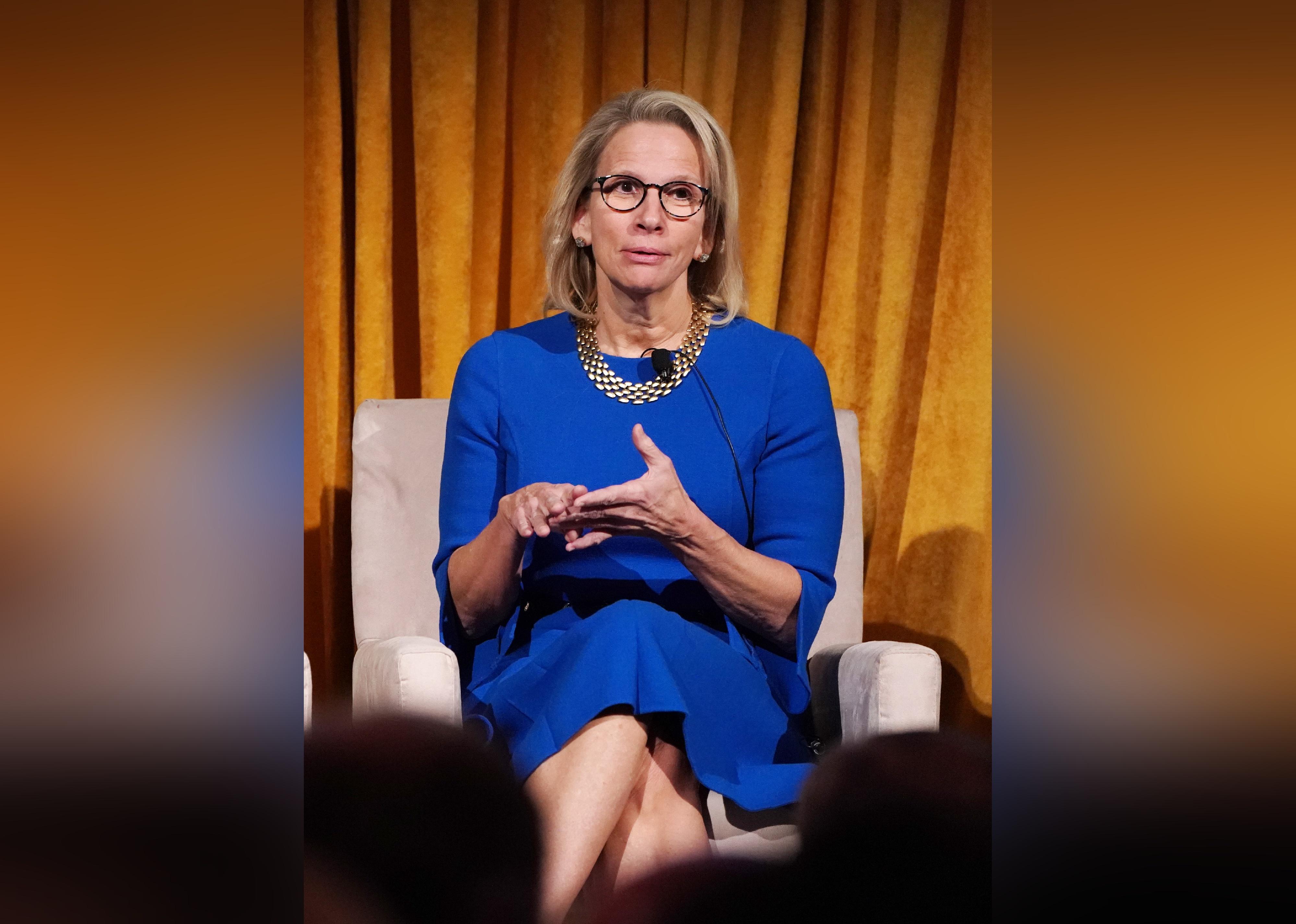 Michele Buck speaks onstage wearing a blue dress.