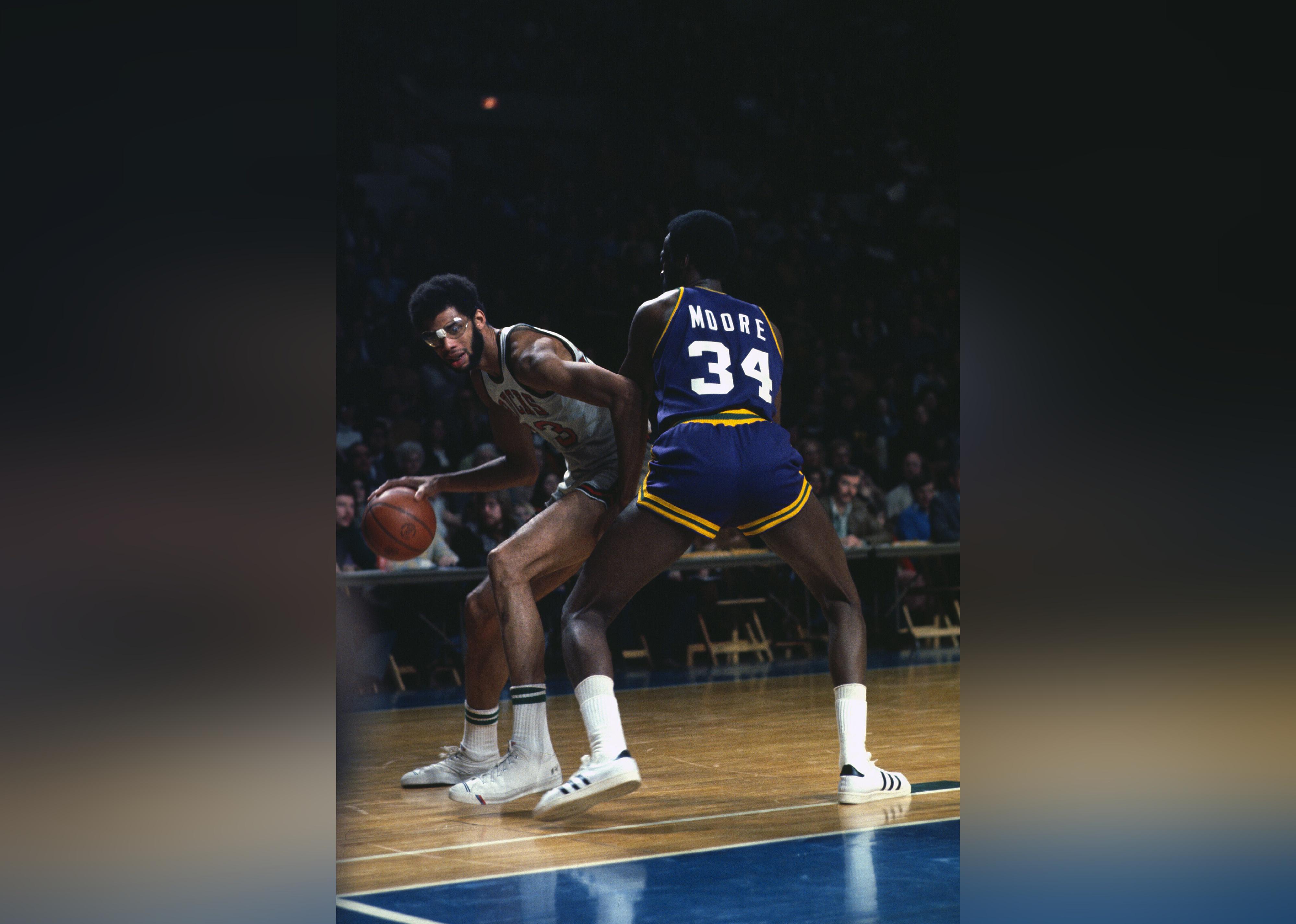  Kareem Abdul-Jabbar dribbles the ball backing in on Otto Moore of the New Orleans Jazz.