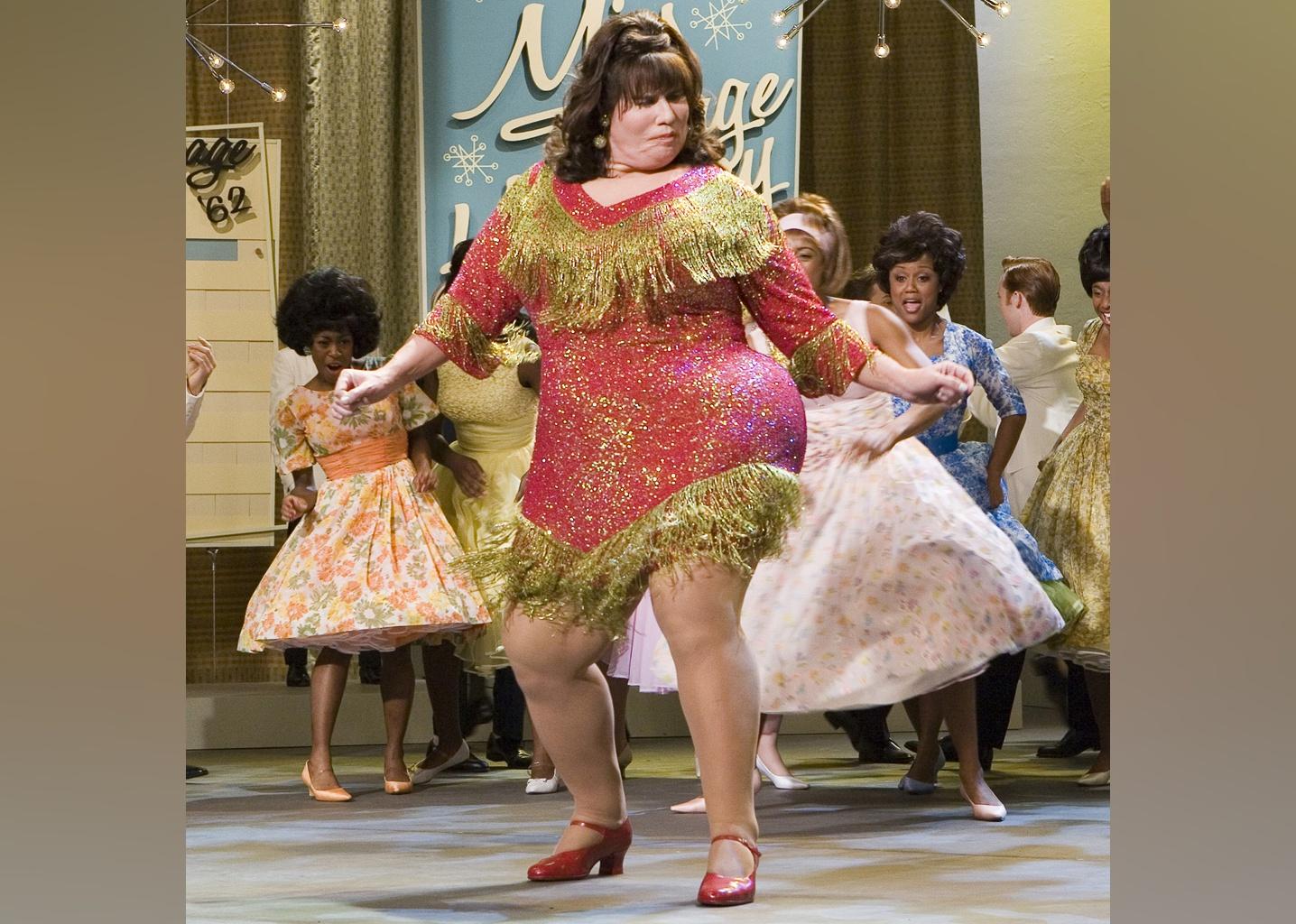 John Travolta dressed as a plump teenager dancing onstage.
