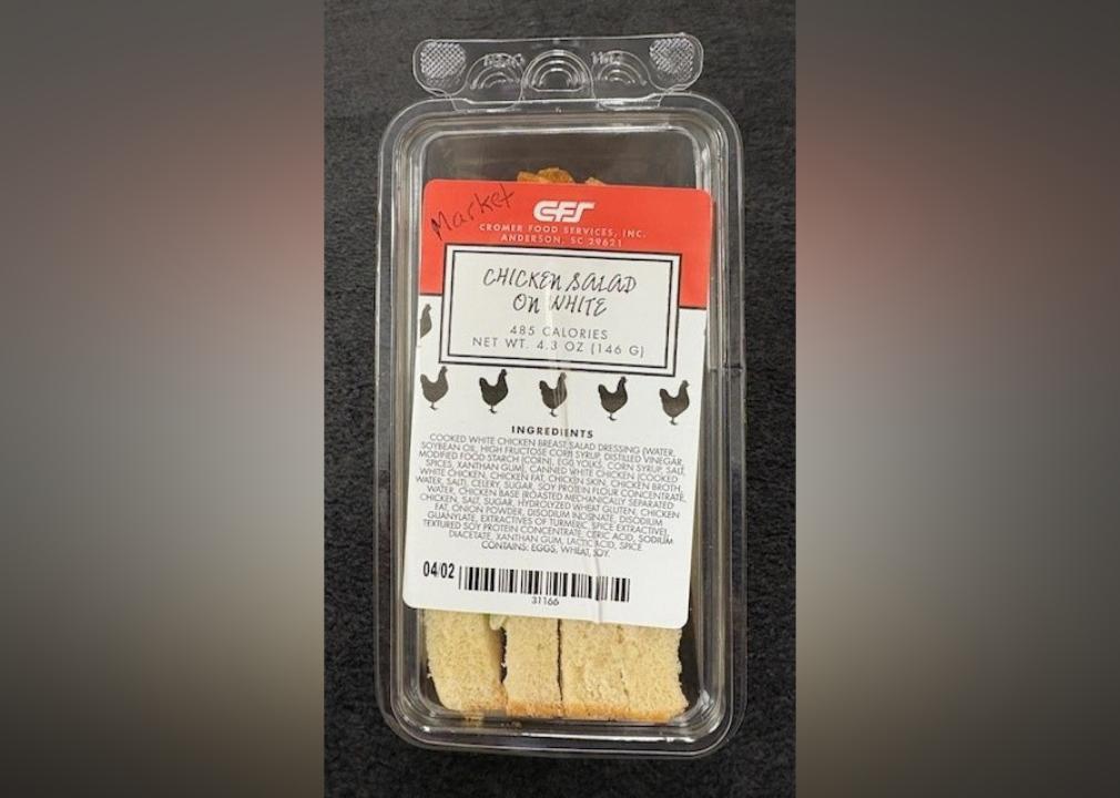 A plastic package with a chicken salad on white sandwich cut in half inside.