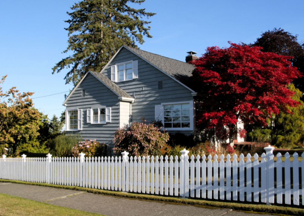 A small grey house with a white picket fence.