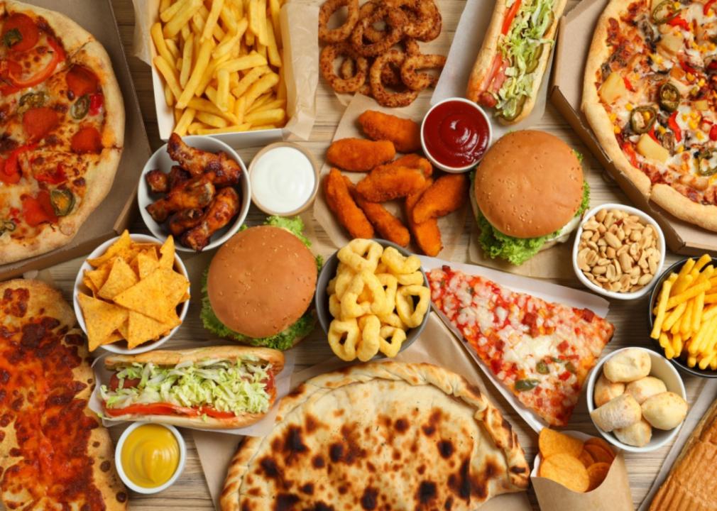 An overhead view of various fast foods, including pizza, calzones, subs, chicken wings, burgers, and fries. 