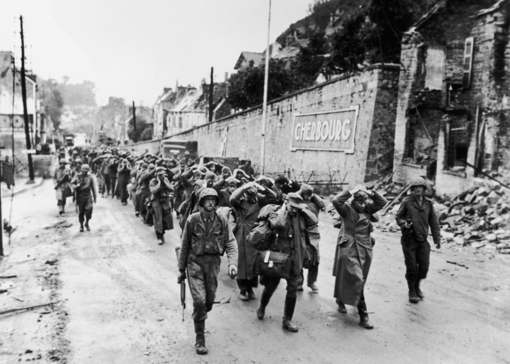 German prisoners carry their fallen comrades to the cemetery in Bréhal, France, in July 1944.