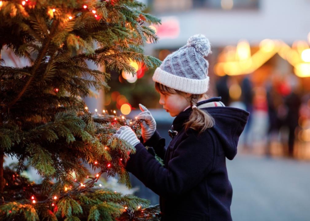 A little girl looking at a Christmas tree.