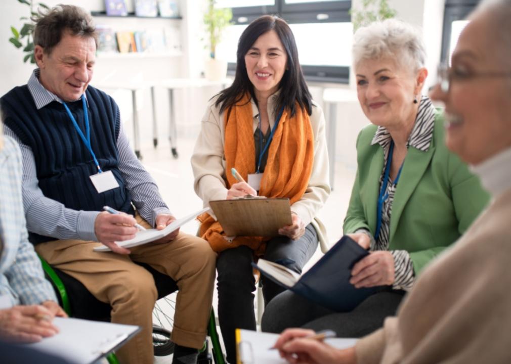 A group of older people having a meeting, sat on chairs set up in a small circle.