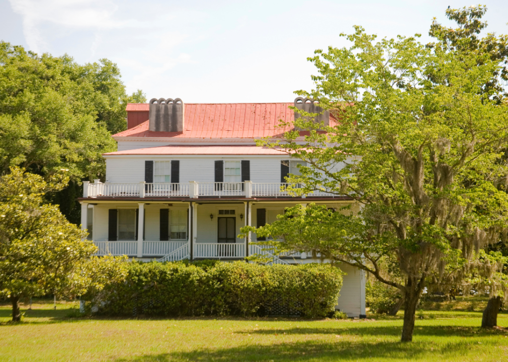 A white historic home with a red roof.