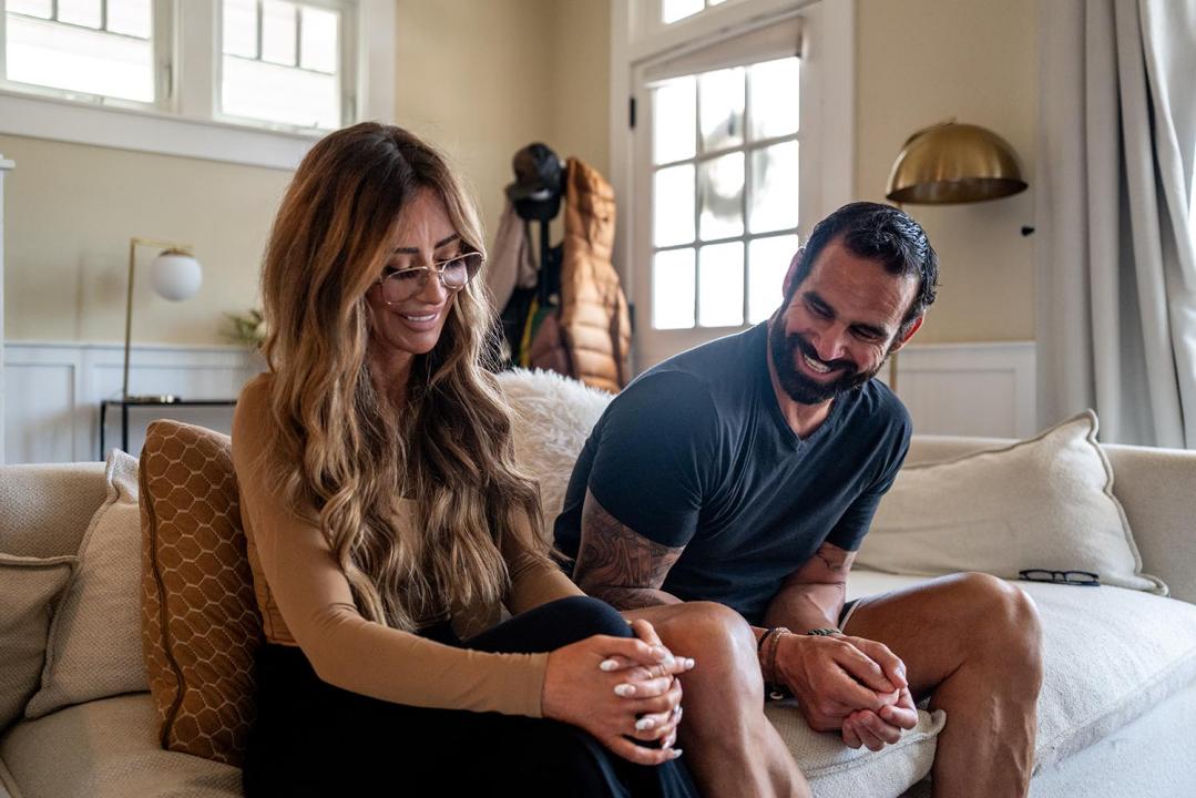 Amber Capone and Marcus Capone sitting together on a white couch.