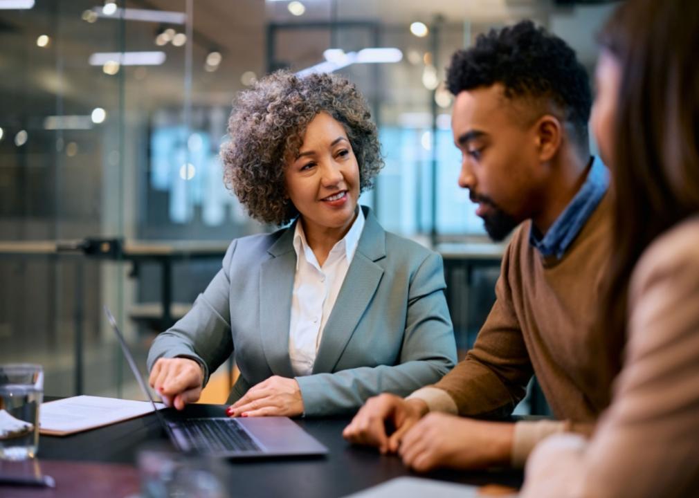 A woman showing something on a computer screen to a man at a desk.