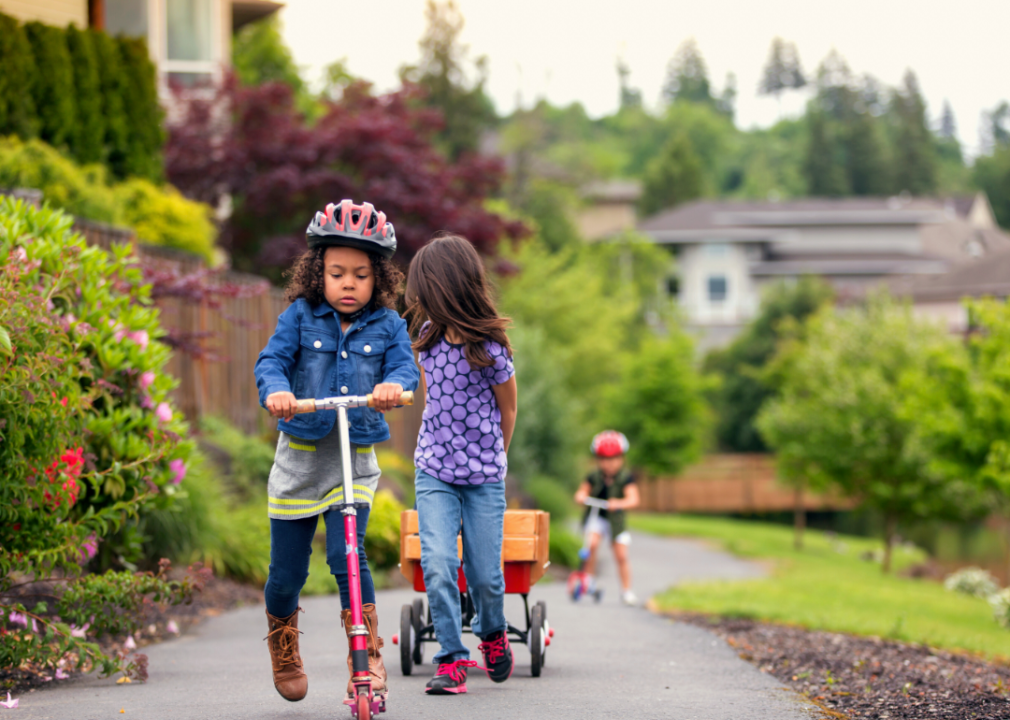 Kids riding scooters on a sidewalk.