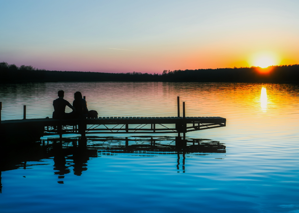 People on a lake dock at sunset.