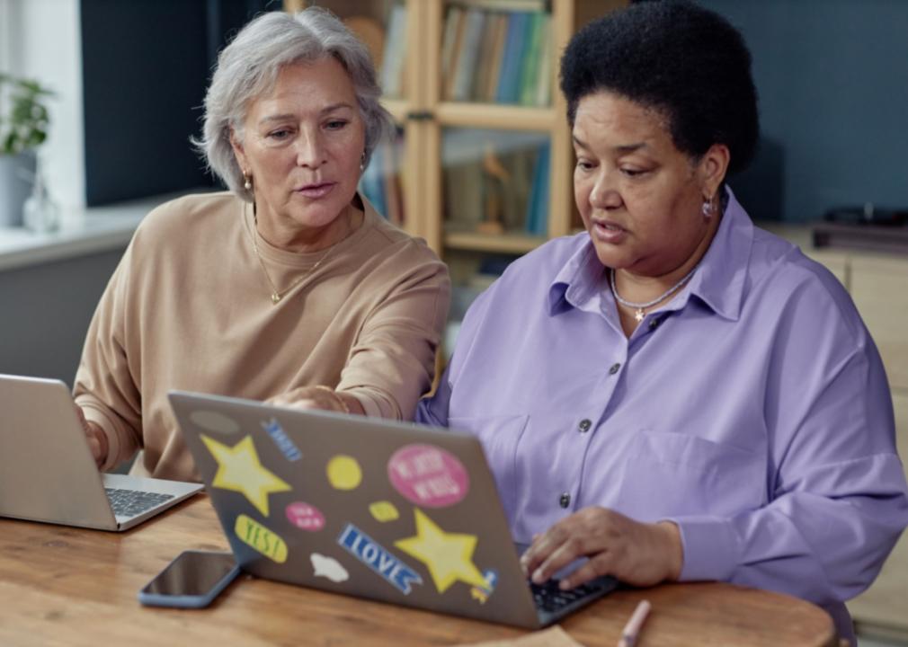 Two women talking while on laptops.