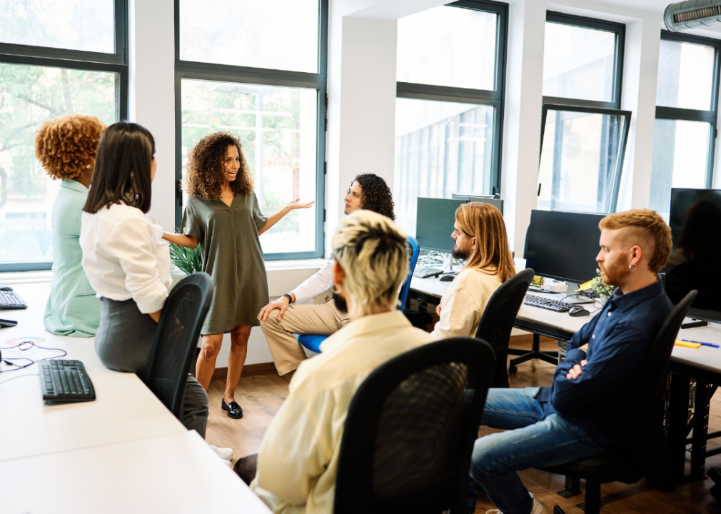 A woman standing and speaking to colleagues.