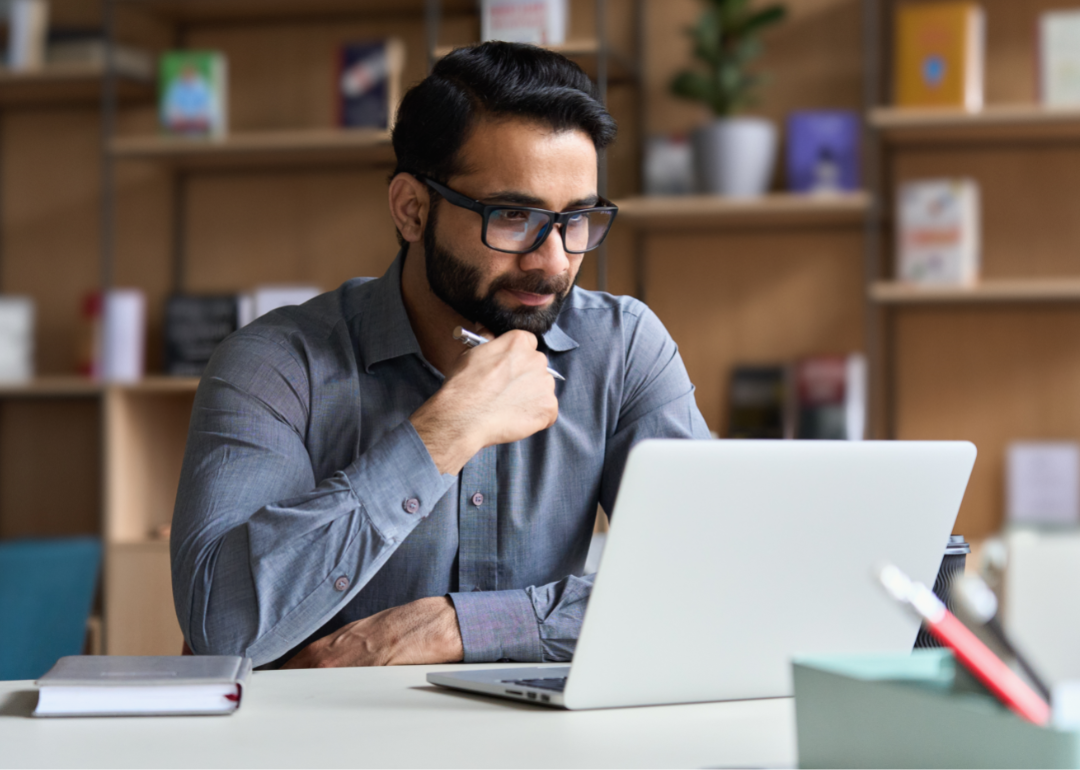 A man with glasses looks intently at his computer screen.