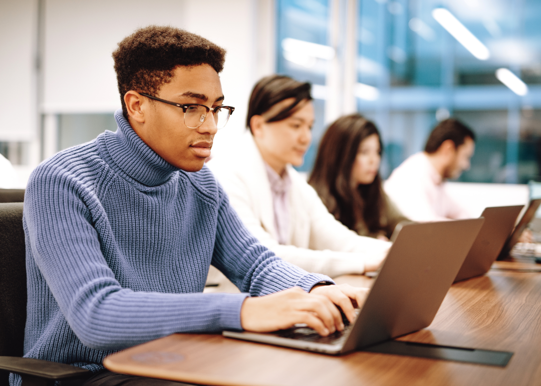 A row of seated workers review documents on their computer screens