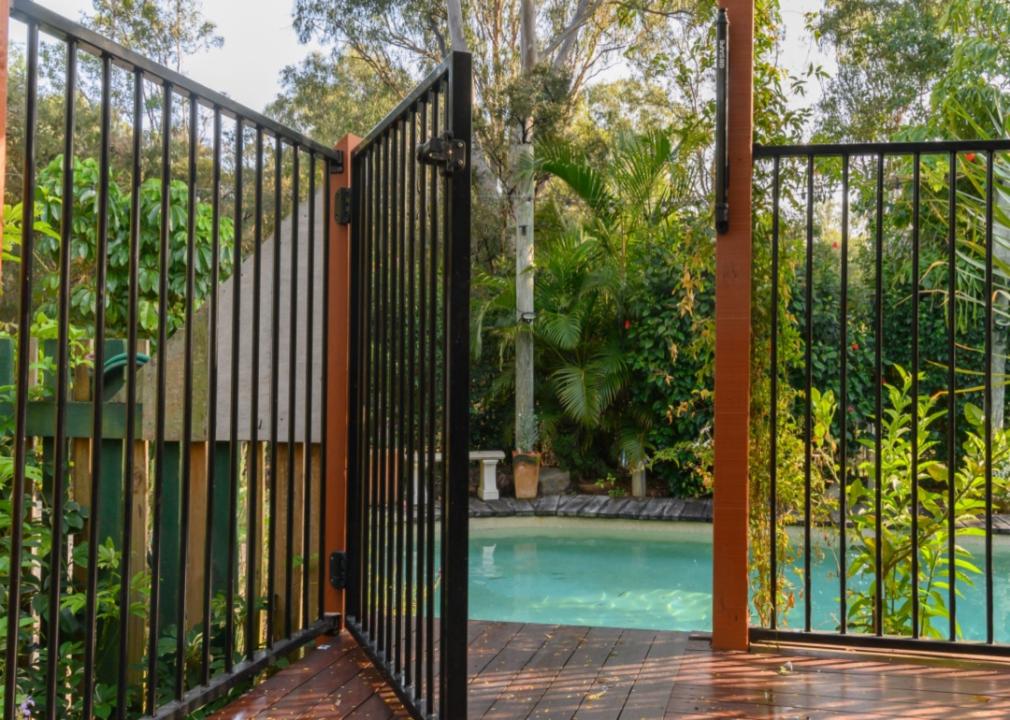 A fence around a pool with a gate open.