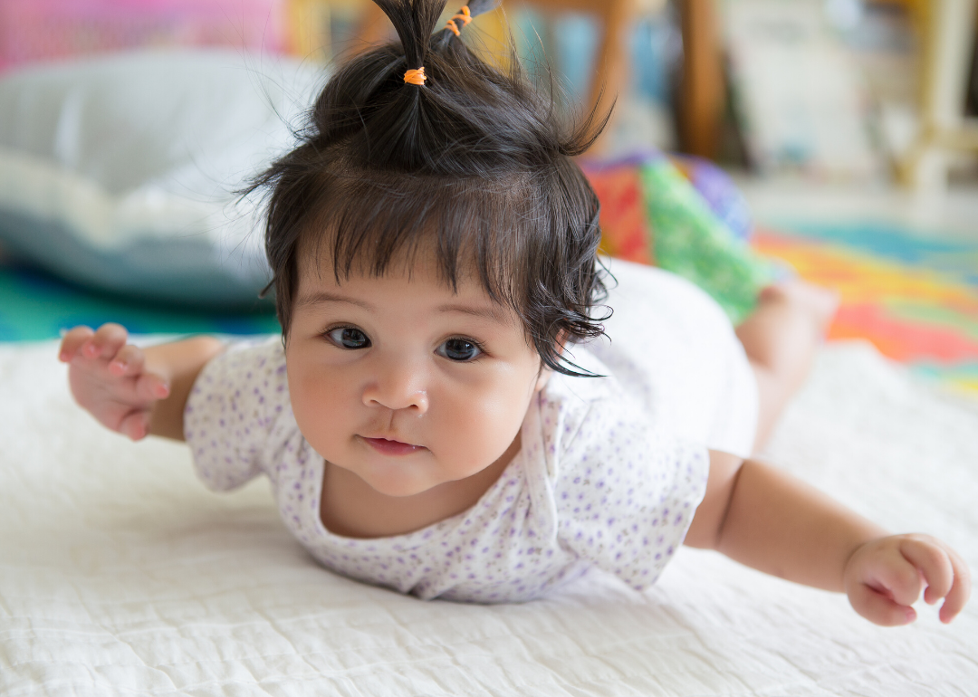 Baby girl laying on stomach on floor.