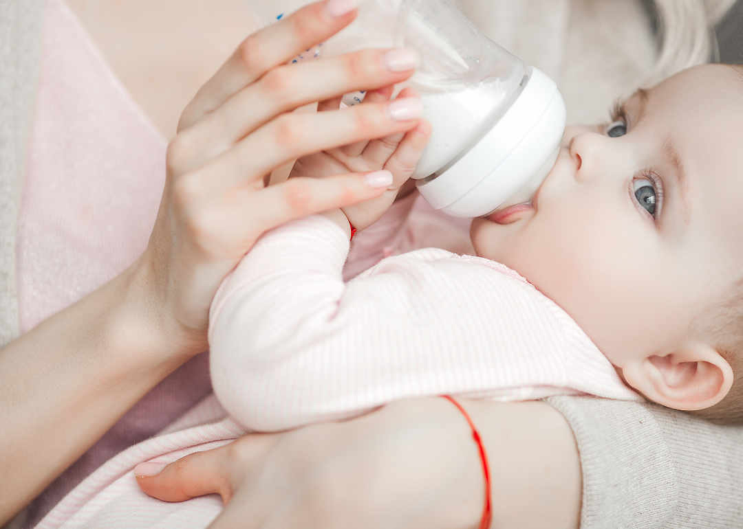 Mother holding baby drinking bottle.