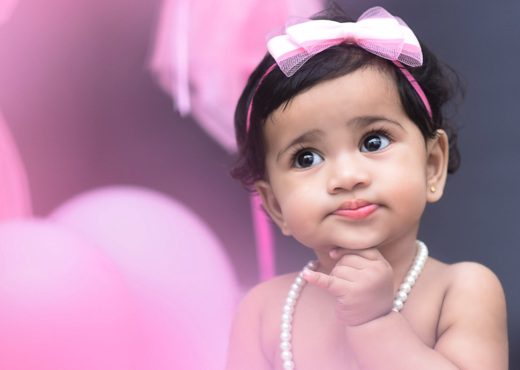 Toddler wearing pink headband and pearls.