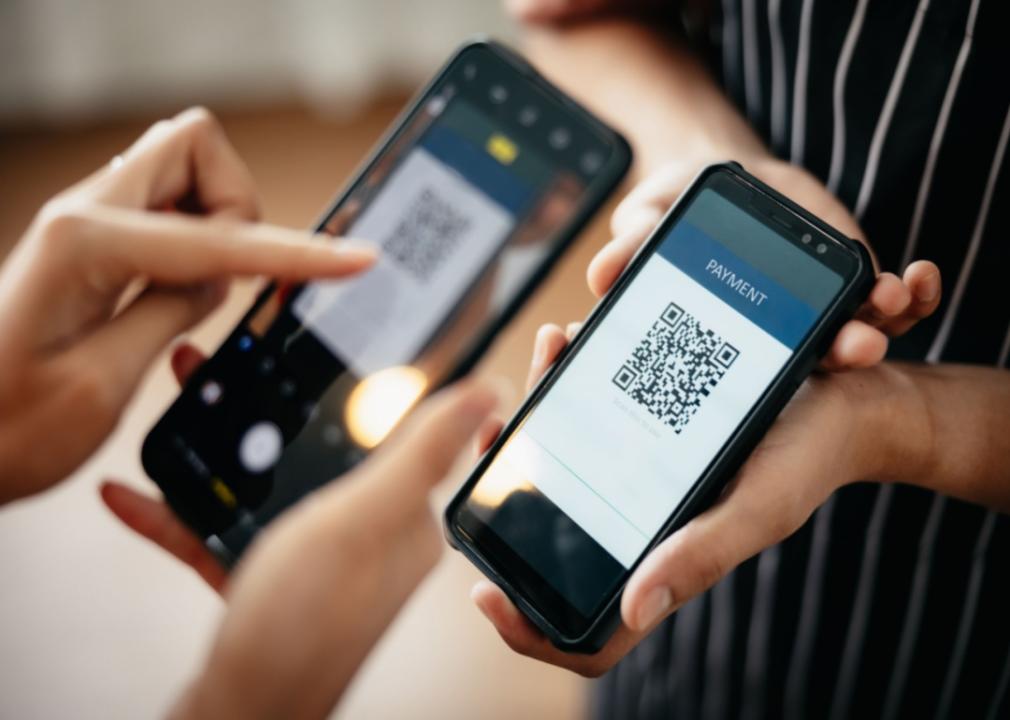 A person uses a device to scan a smartphone with a QR code.