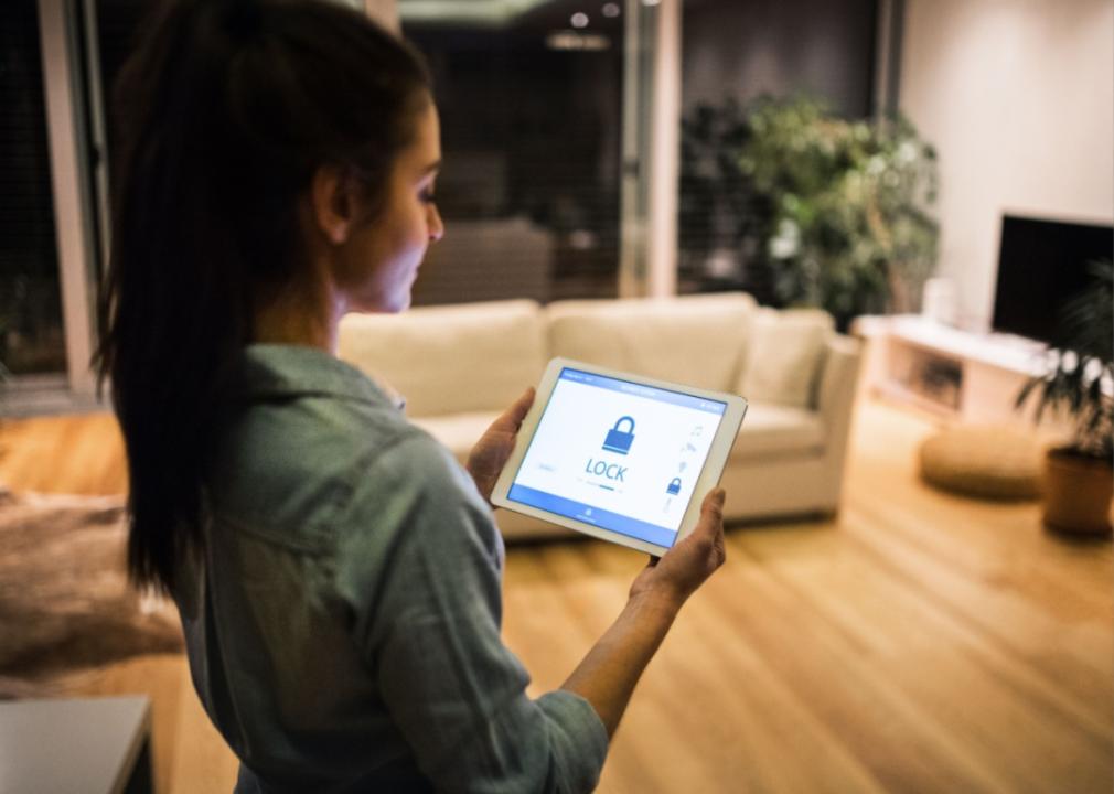 A woman checking a security system on a tablet.