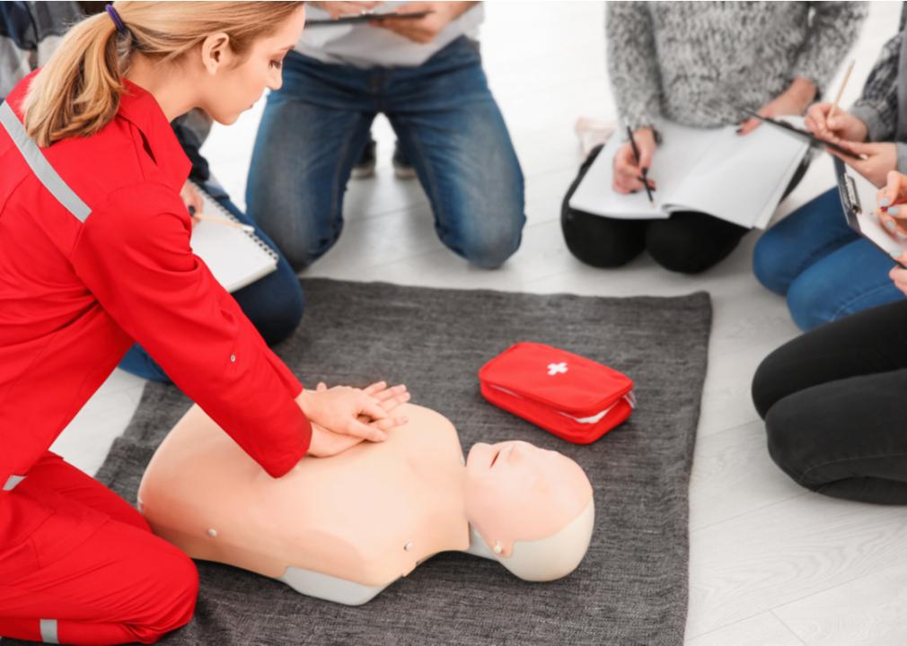 A woman demonstrating CPR on mannequin during a first aid class