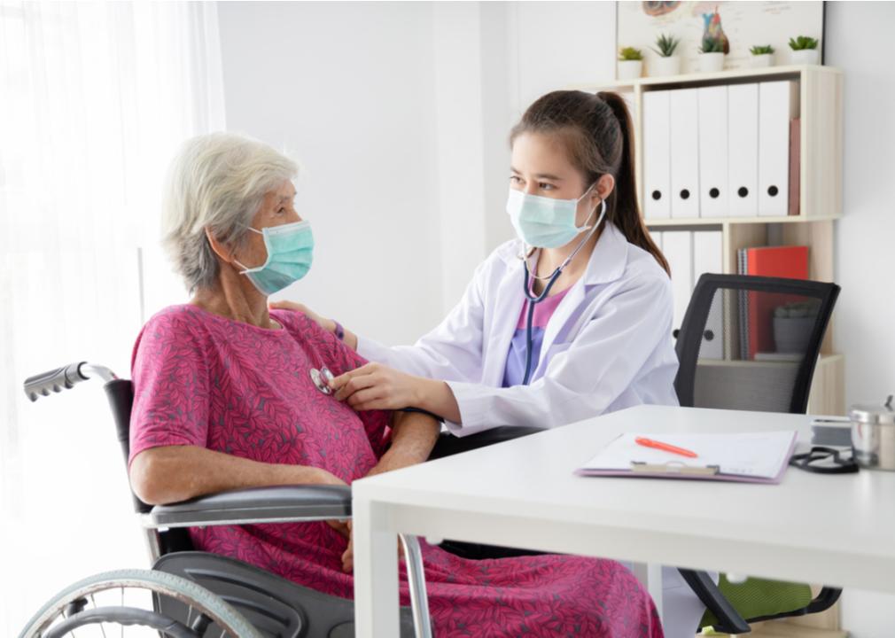 An elderly woman wearing a surgical mask while visiting a doctor