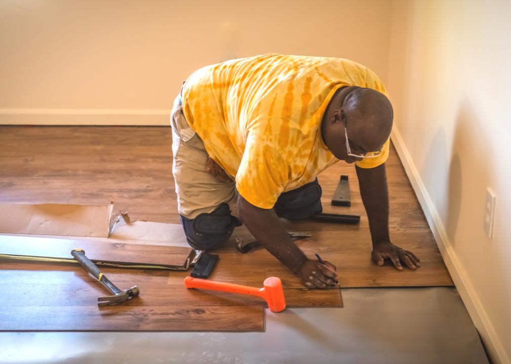 A carpenter working to install a  new laminated floor in a residential home