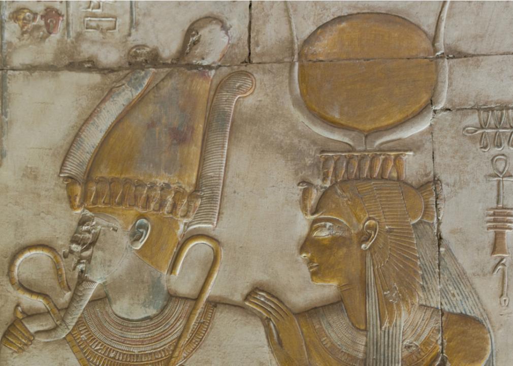 A carving of Isis standing behind Osiris at Abydos Temple